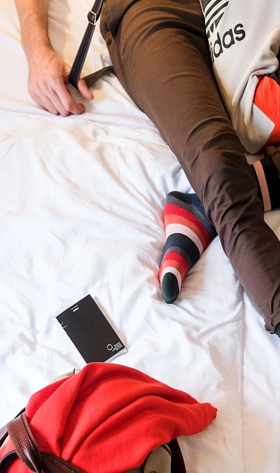 Ein Bett auf dem eine Person und eine Tasche liegt.