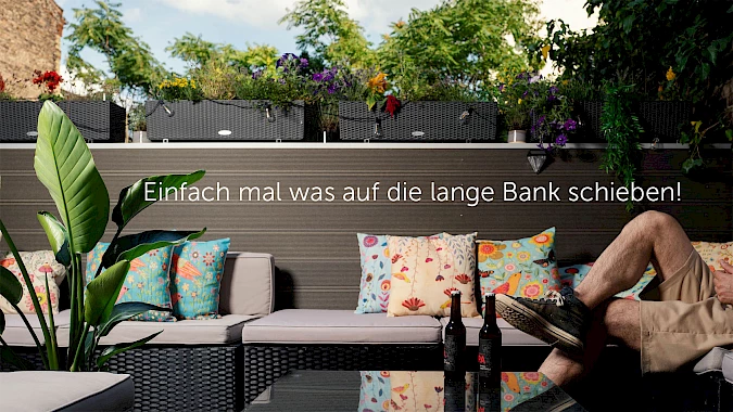 Eine Person sitzt in einer Balkon-Lounge mit vielen Blumen.