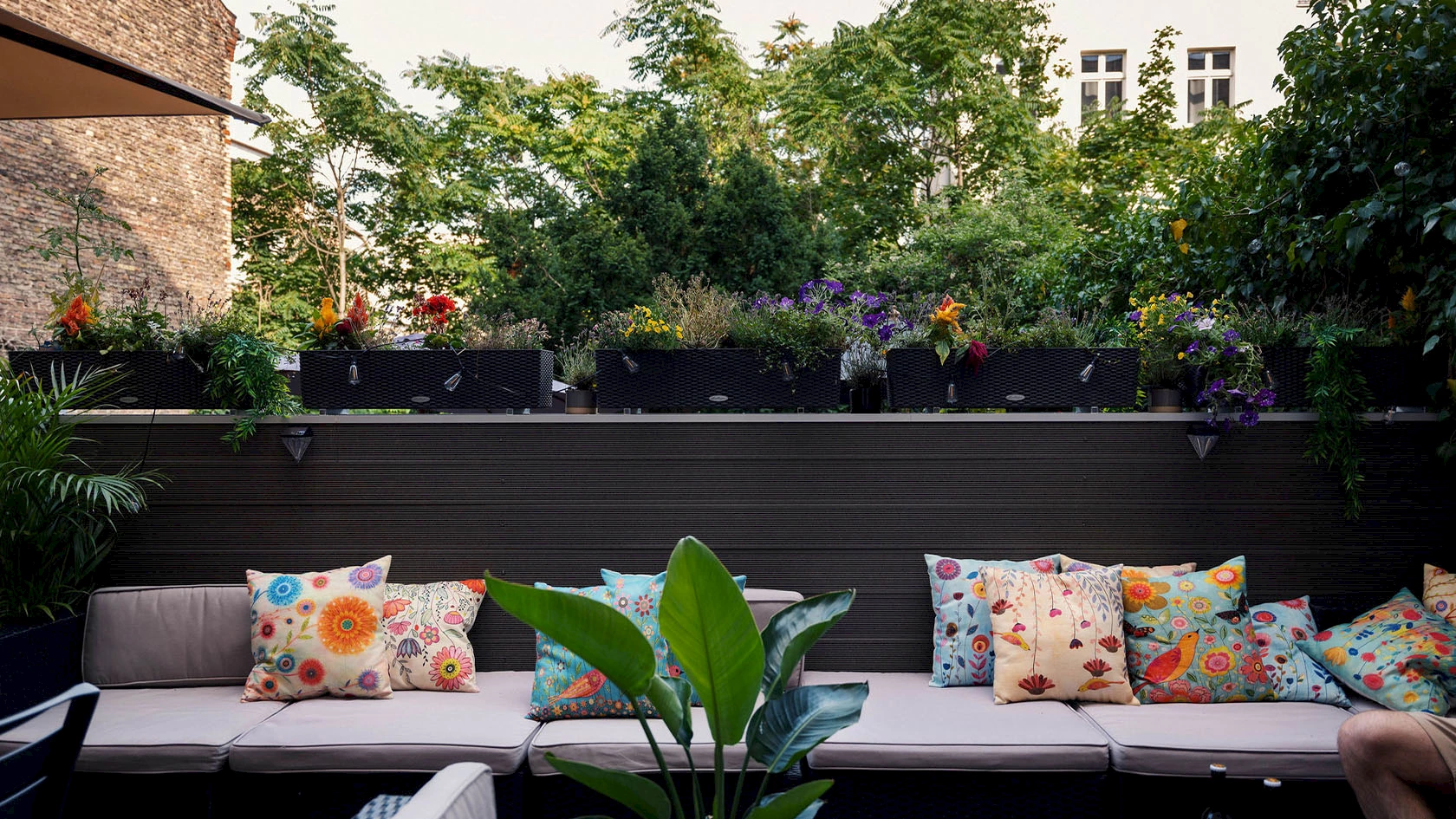 Eine Balkon-Lounge mit vielen Blumen.