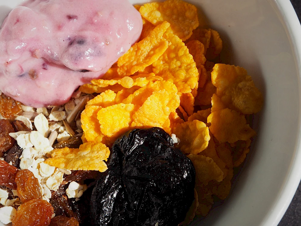 Eine kleine Schüssel mit Cornflakes, Müsli und Joghurt.