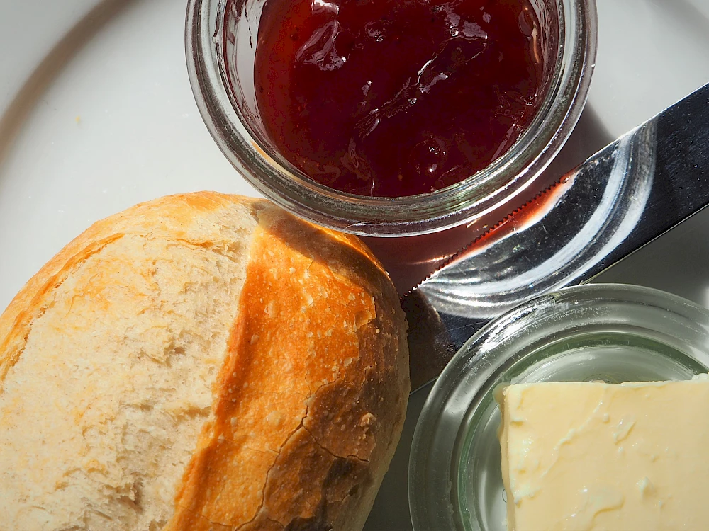 Ein Teller mit einem Brötchen, Marmelade und Butter.