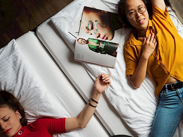 Zwei junge Personen liegen auf einem Bett.