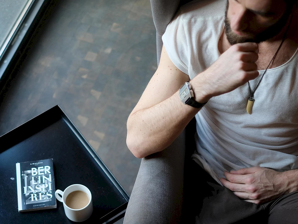 Eine Person sitzt in einem Sessel und trinkt einen Kaffee.